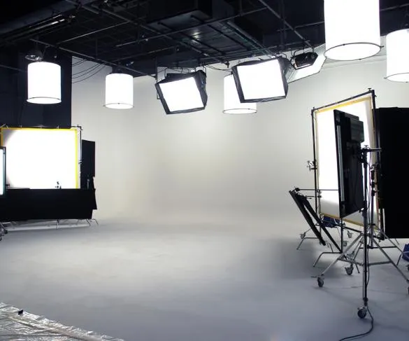 A professional photography studio setup with softbox lights, reflectors, and a plain white backdrop is shown.