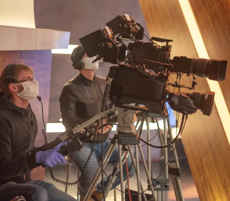 Two cameramen wearing masks behind cameras