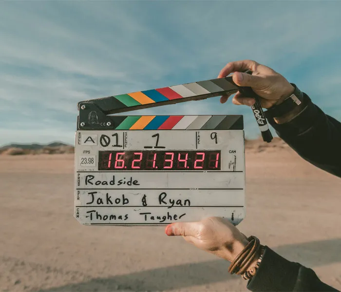 Close-up of hands holding a film clapperboard outdoors, with 