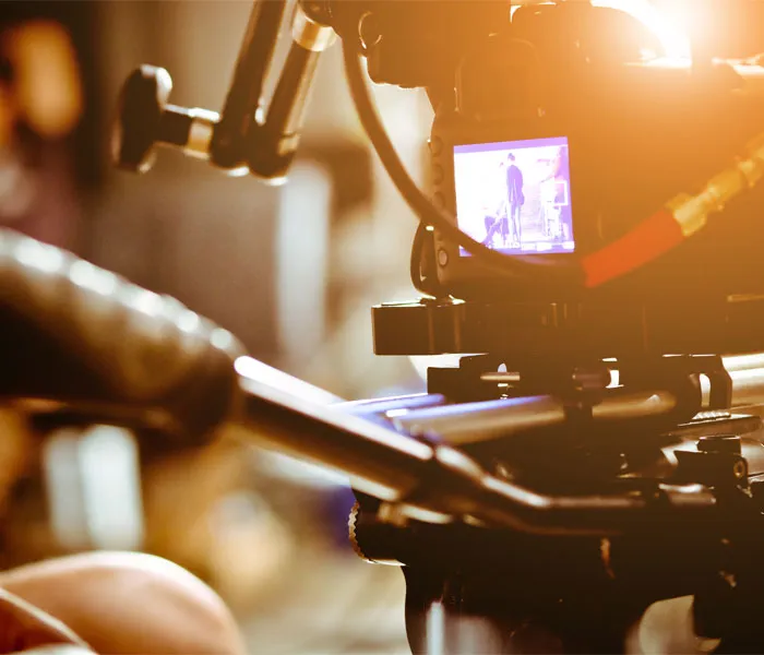 Close-up of a camera setup capturing a scene, with the camera monitor showing an individual standing in the background.