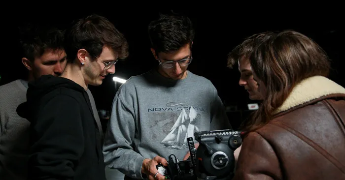 Several people standing together around a camera, sharing smiles and enjoying a collaborative photography experience.