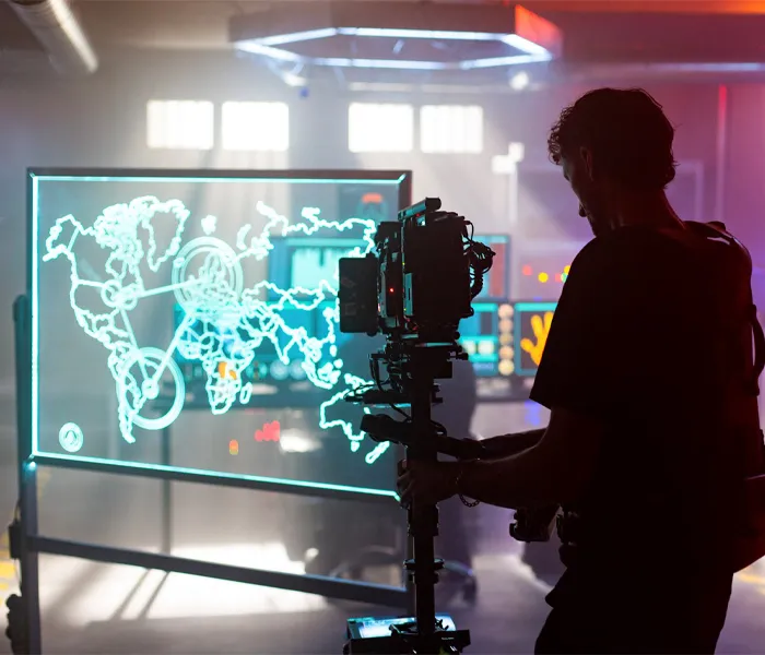 A man stands before a screen displaying a detailed map, engaged in observation or analysis of the information presented.